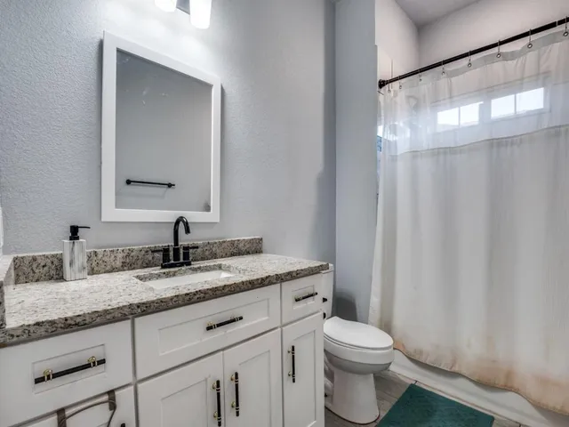 a bathroom with a granite countertop sink toilet and mirror