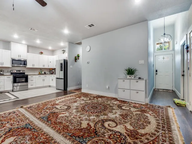 a living room with stainless steel appliances kitchen island granite countertop a refrigerator and a stove top oven