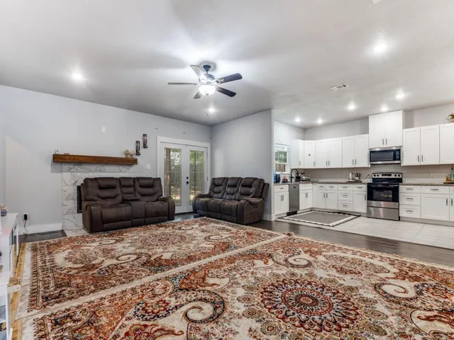 a large kitchen with kitchen island granite countertop a stove a sink a counter top space and cabinets