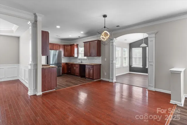 an open kitchen with a refrigerator and wooden floor