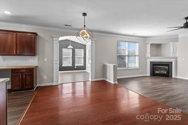 a view of an empty room with wooden floor fireplace and a window