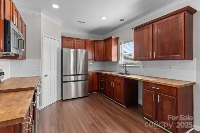 a kitchen with stainless steel appliances granite countertop a refrigerator a sink dishwasher a stove with wooden cabinets and floor