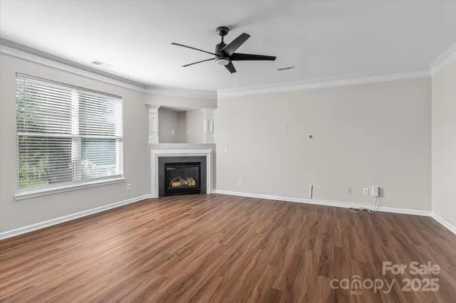 an empty room with wooden floor a fireplace and windows