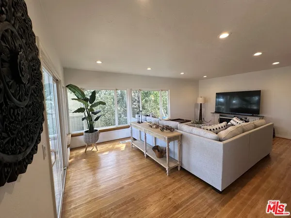 a kitchen with stainless steel appliances granite countertop a stove a sink dishwasher a microwave oven and a dining table with wooden floor