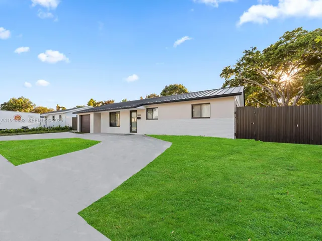 a view of a house with a big yard plants and large trees
