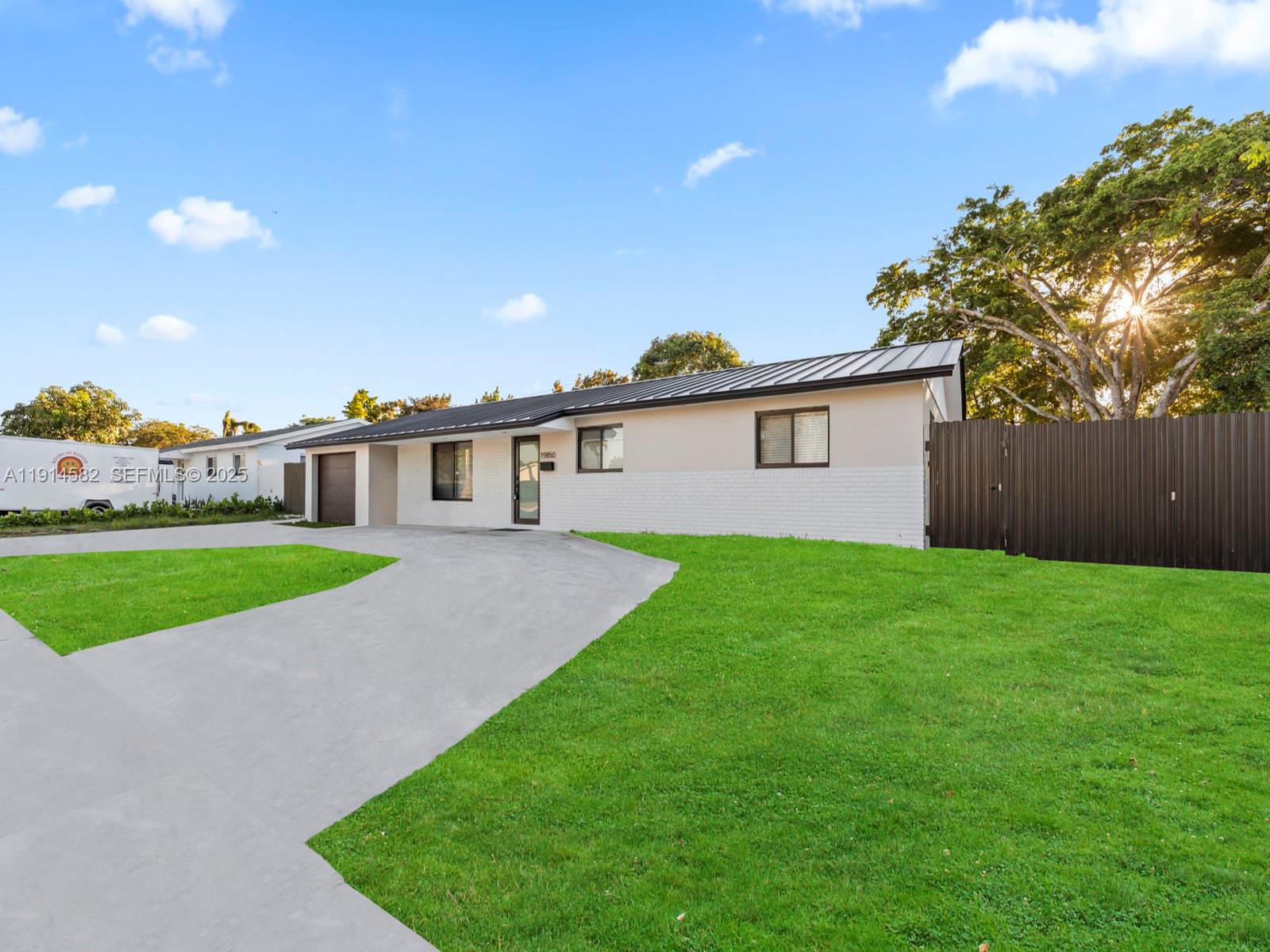 a view of a house with a big yard plants and large trees