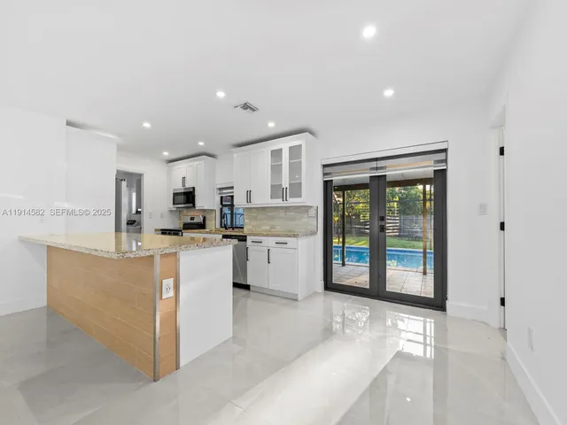 a kitchen with kitchen island granite countertop a stove sink and microwave