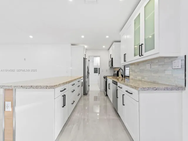 a kitchen with stainless steel appliances granite countertop a refrigerator a stove and a sink