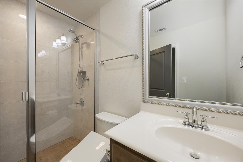 918 Sydney Lane Allen, TX 75013 - Photo 28 of 40 Bathroom 4 featuring a glass-enclosed shower, a vanity with a white countertop and chrome faucet, and a large mirror with an ornate frame