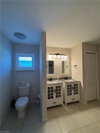 a view of a bathroom with a toilet a sink a mirror and a racks