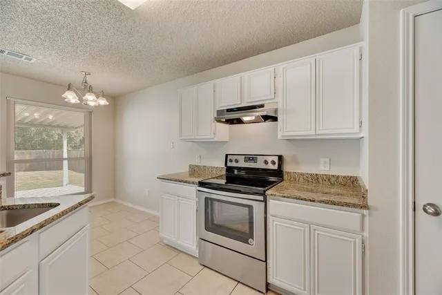 a kitchen with granite countertop white cabinets and appliances