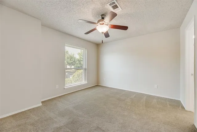 an empty room with windows and fan