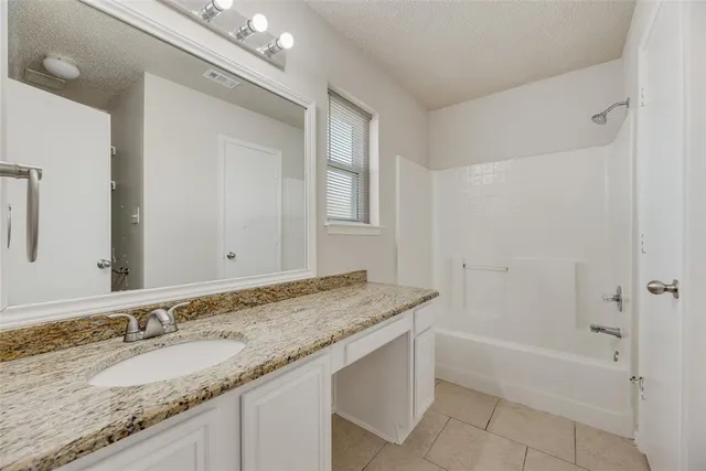 a bathroom with a granite countertop sink mirror and a bath tub