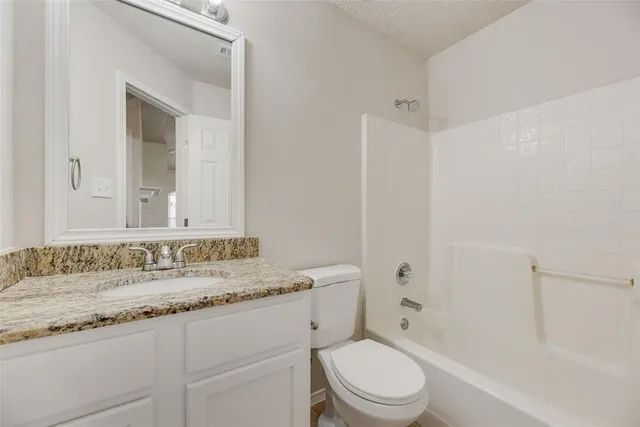 a bathroom with a granite countertop sink a mirror and a toilet