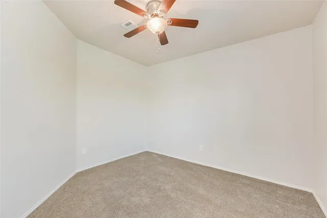 an empty room with a window and a fan