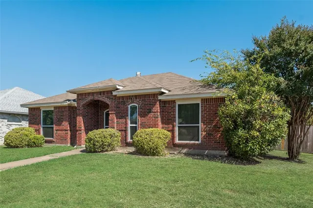 a view of a house with brick walls and a yard with plants