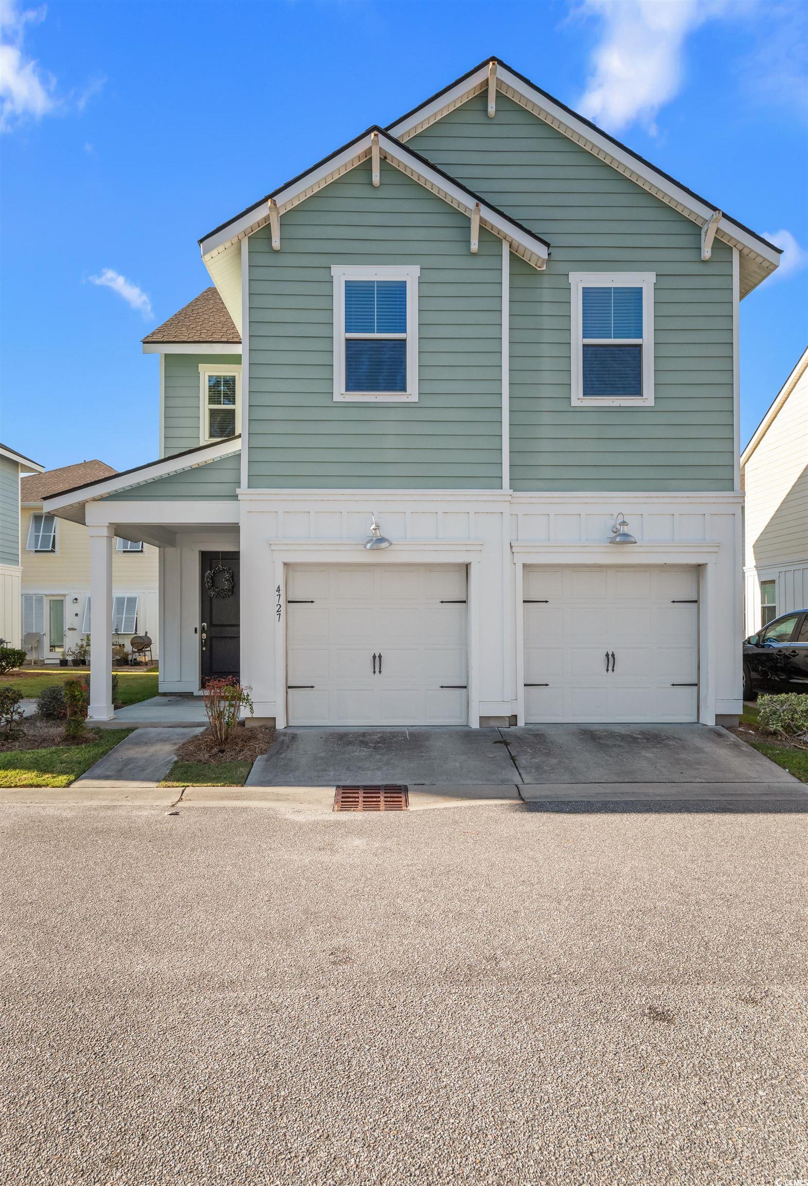 View of front of house with an attached garage, a porch, and driveway