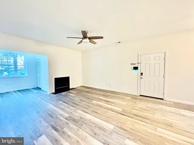 a view of empty room with wooden floor and ceiling fan