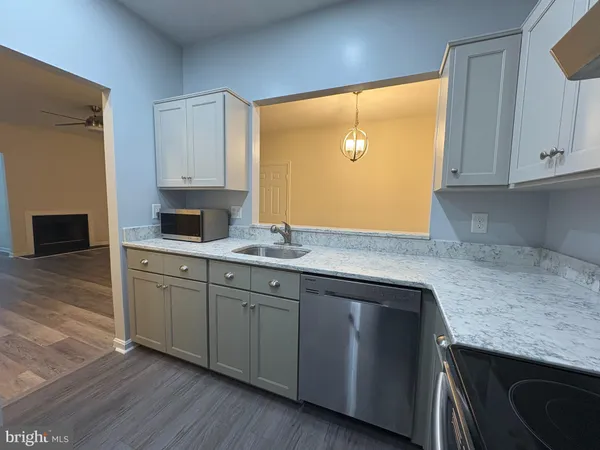 a kitchen with granite countertop cabinets stainless steel appliances a sink and wooden floor