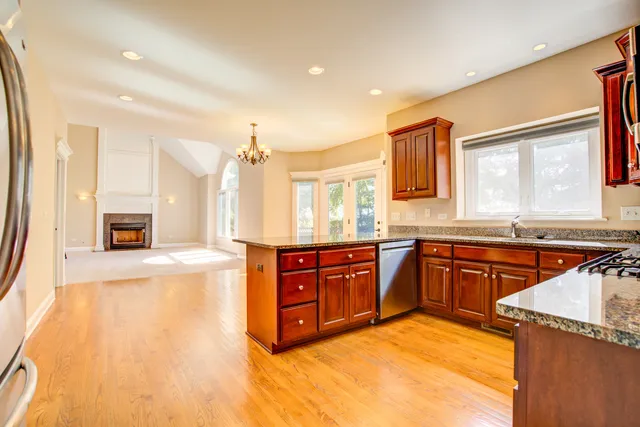 a large kitchen with stainless steel appliances granite countertop a sink and cabinets with wooden floor