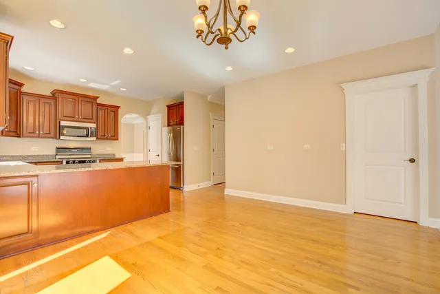 a view of kitchen with stainless steel appliances granite countertop a stove a sink and a refrigerator with wooden floor