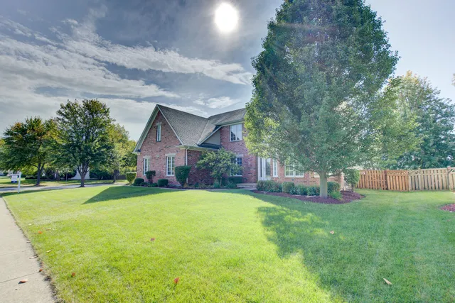 a view of a house with a yard and a large tree
