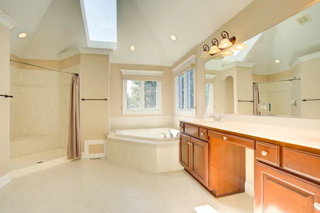 a spacious bathroom with a shower a large mirror and a bathtub