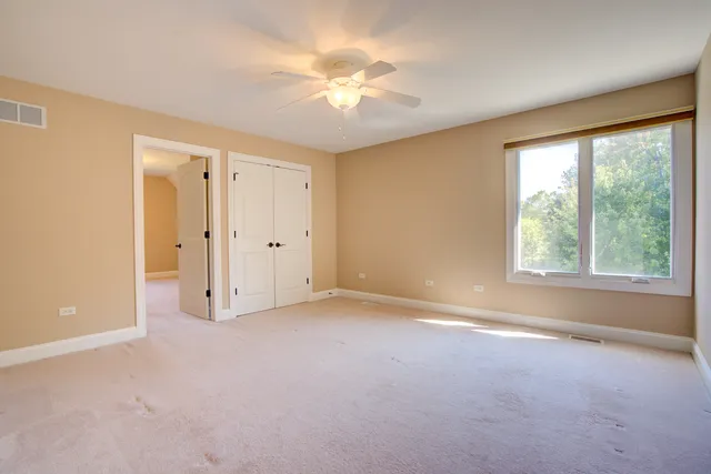 an empty room with chandelier fan and windows