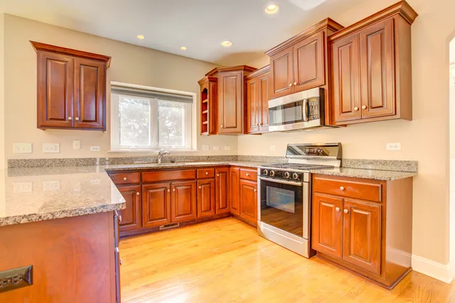a kitchen with stainless steel appliances granite countertop a stove a sink and a microwave
