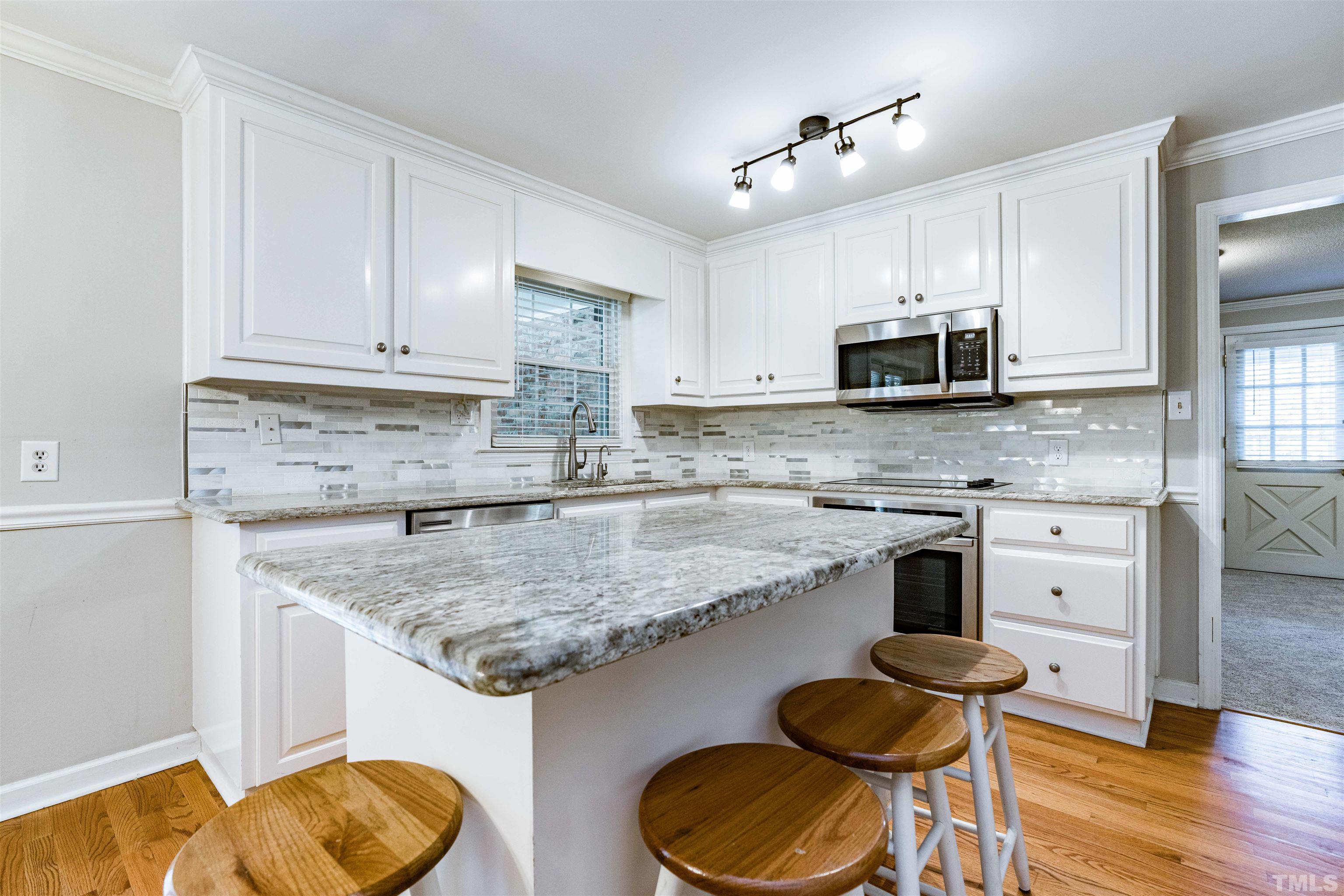 103 Marilyn Circle Cary, NC 27513 - Photo 11 of 64 a kitchen with stainless steel appliances granite countertop a sink dishwasher a stove and a microwave oven with wooden floor