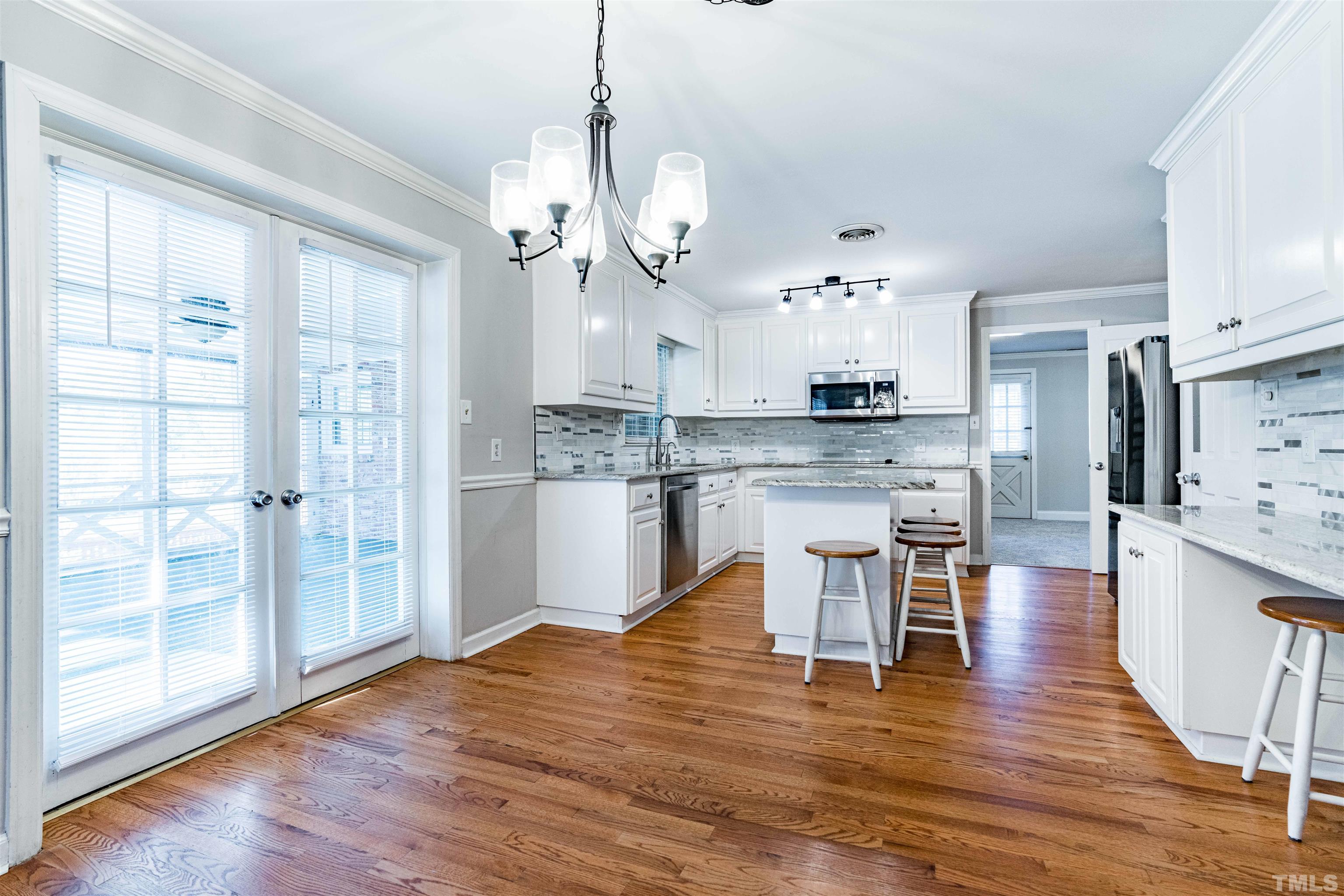 103 Marilyn Circle Cary, NC 27513 - Photo 8 of 64 a large kitchen with stainless steel appliances kitchen island granite countertop a stove a refrigerator a sink dishwasher a dining table and chairs with wooden floor