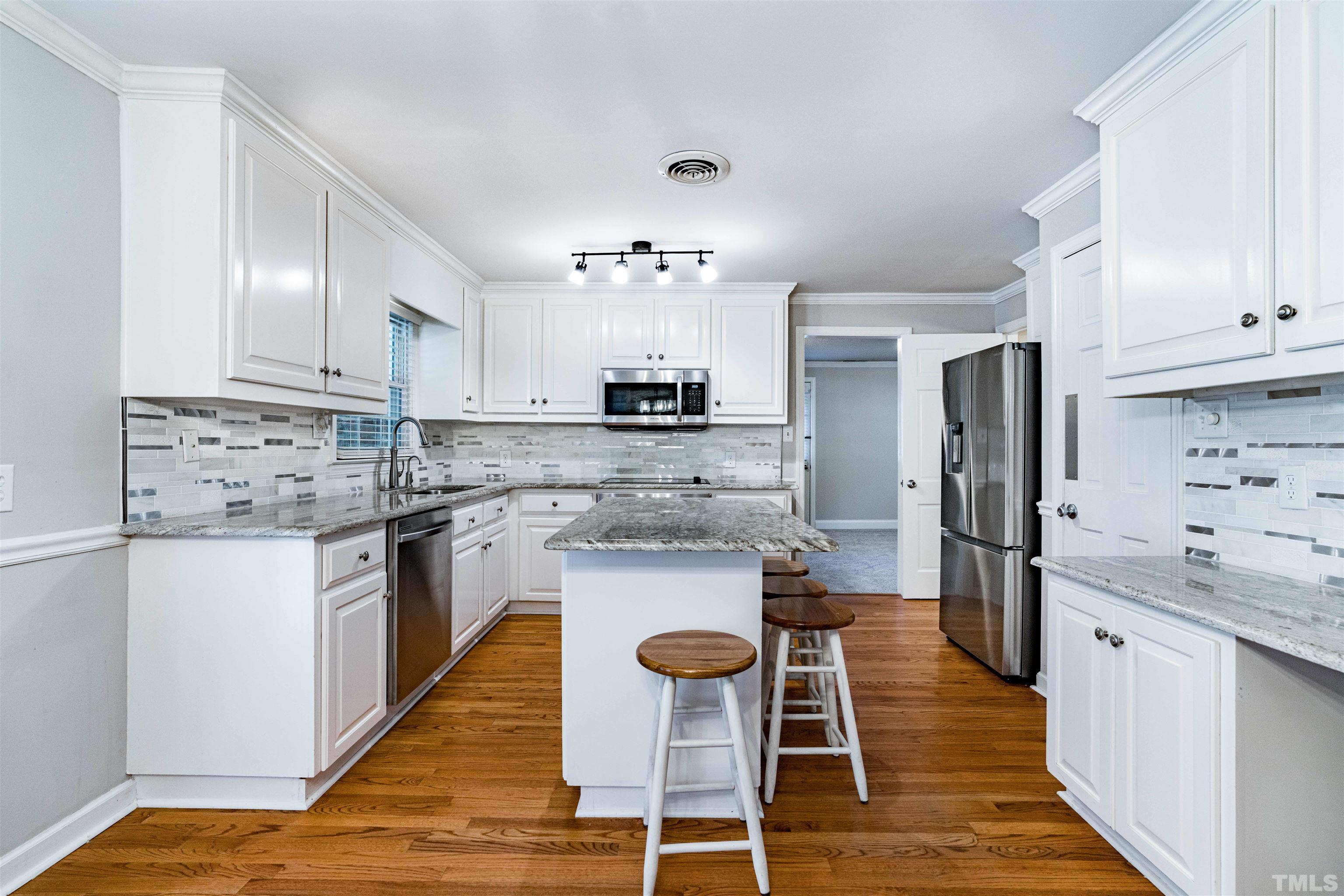 103 Marilyn Circle Cary, NC 27513 - Photo 10 of 64 a kitchen with stainless steel appliances granite countertop a kitchen island hardwood floor sink stove and white cabinets
