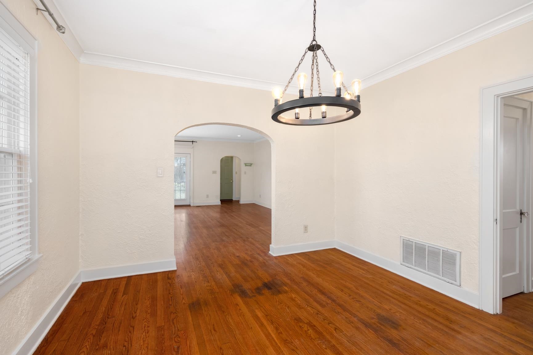 331 Alexander Street Memphis, TN 38111 - Photo 10 of 25 Unfurnished dining area featuring arched walkways, crown molding, dark wood-style flooring, and a chandelier