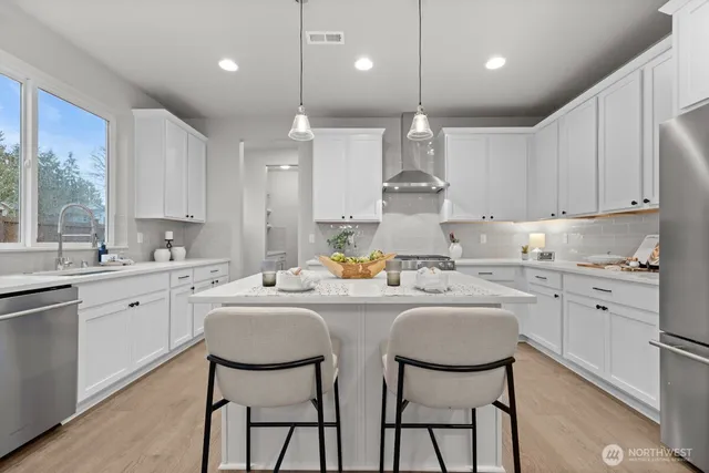 a kitchen that has a lot of white cabinets and stainless steel appliances