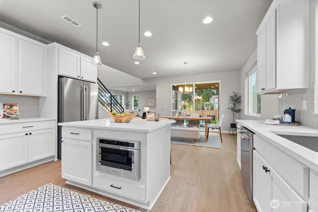 a kitchen with a stove a refrigerator and white cabinets with wooden floor
