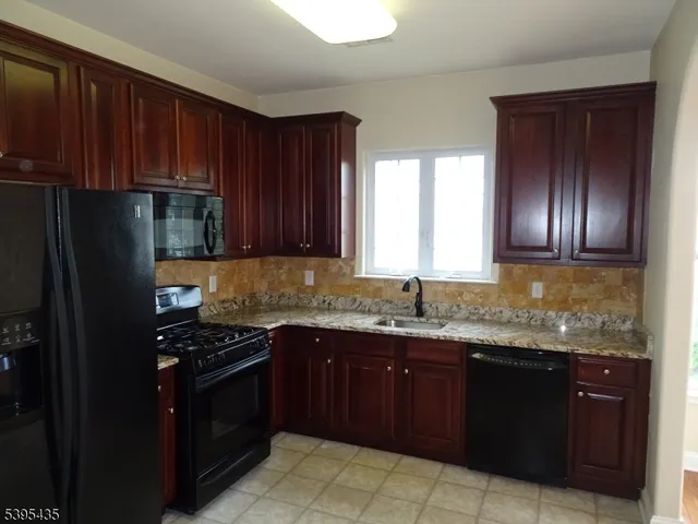 a kitchen with granite countertop stainless steel appliances a stove sink and cabinets