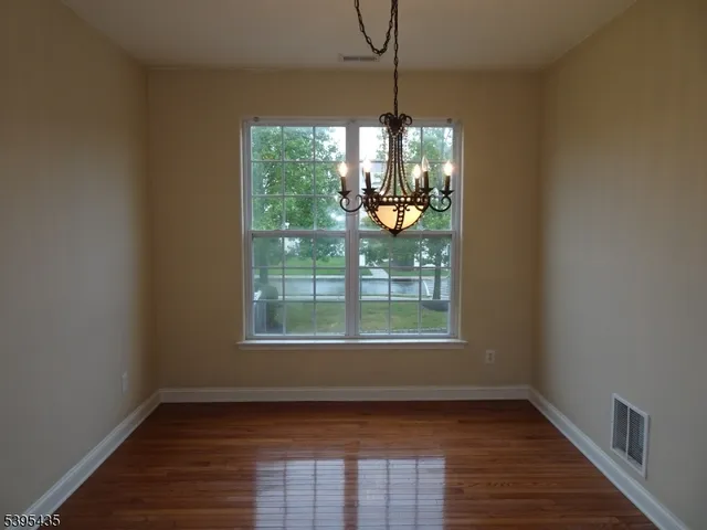 a view of an empty room with window wooden floor and chandelier