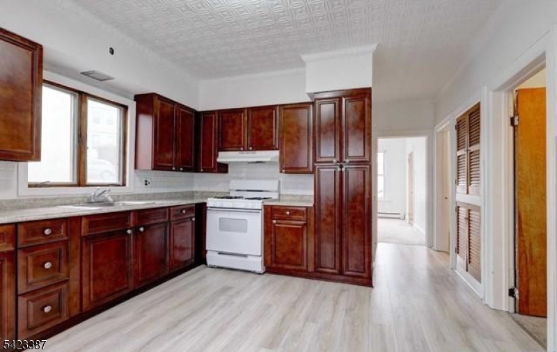 58 Westervelt Avenue Hawthorne, NJ 07506 - Photo 3 of 14 a kitchen with stainless steel appliances granite countertop a refrigerator a sink dishwasher and wooden cabinets with wooden floor