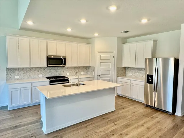 a kitchen with stainless steel appliances a refrigerator sink and microwave