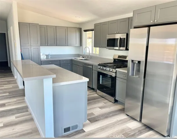 a kitchen with stainless steel appliances granite countertop a refrigerator a stove top oven a sink and dishwasher