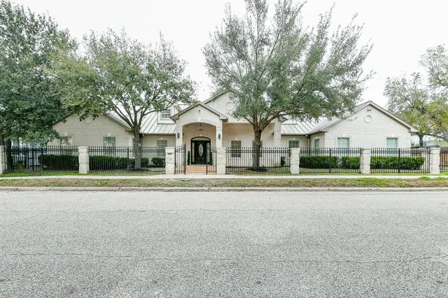 a view of a white house with a yard and large trees