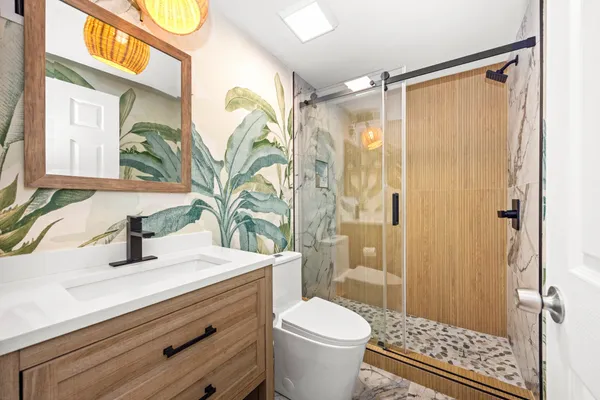 a bathroom with a sink a toilet a glass door a shower and a mirror