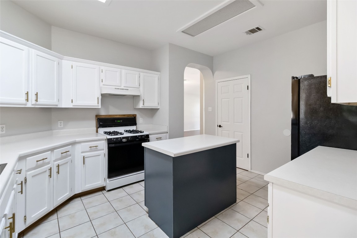 1320 Lochaline Loop Pflugerville, TX 78660 - Photo 11 of 35 Kitchen featuring a kitchen island, white cabinetry, range with gas cooktop, freestanding refrigerator, and light countertops