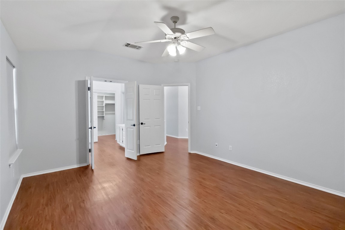 1320 Lochaline Loop Pflugerville, TX 78660 - Photo 17 of 35 Unfurnished bedroom with a spacious closet, dark wood finished floors, a ceiling fan, and vaulted ceiling