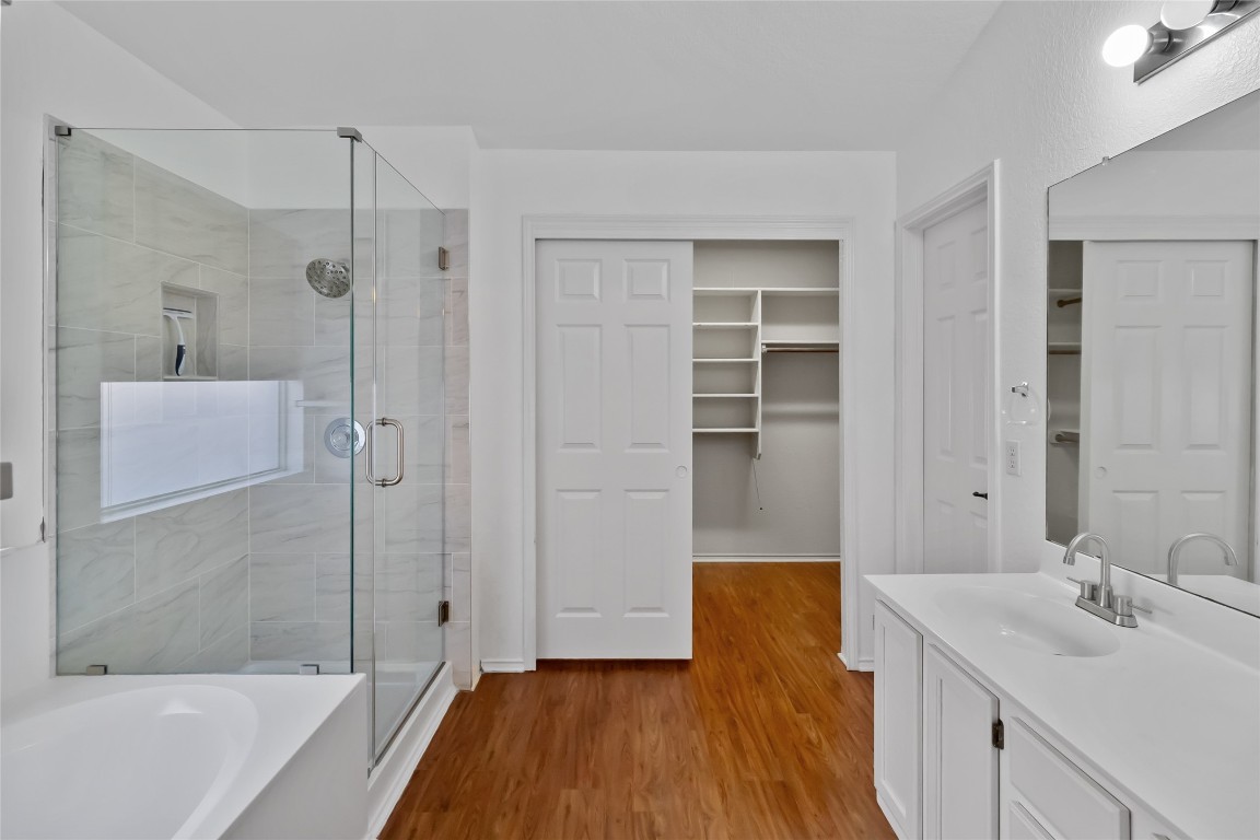 1320 Lochaline Loop Pflugerville, TX 78660 - Photo 18 of 35 Full bath with vanity, light wood finished floors, a spacious closet, a stall shower, and a bathtub