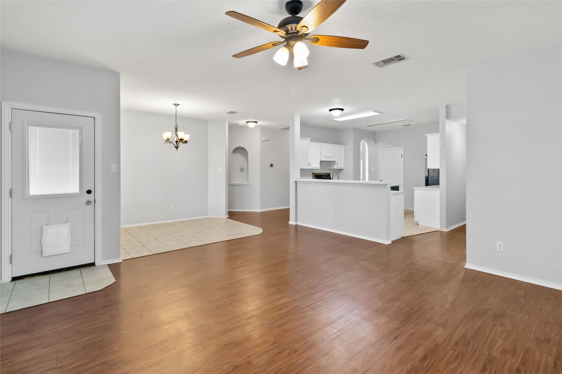 1320 Lochaline Loop Pflugerville, TX 78660 - Photo 22 of 35 Unfurnished living room featuring dark wood-style floors, arched walkways, a ceiling fan, and a chandelier