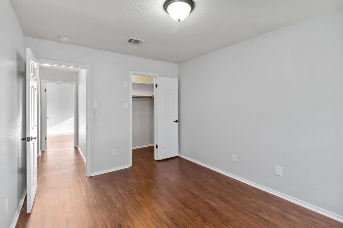 1320 Lochaline Loop Pflugerville, TX 78660 - Photo 25 of 35 Unfurnished bedroom featuring a walk in closet and dark wood-style floors