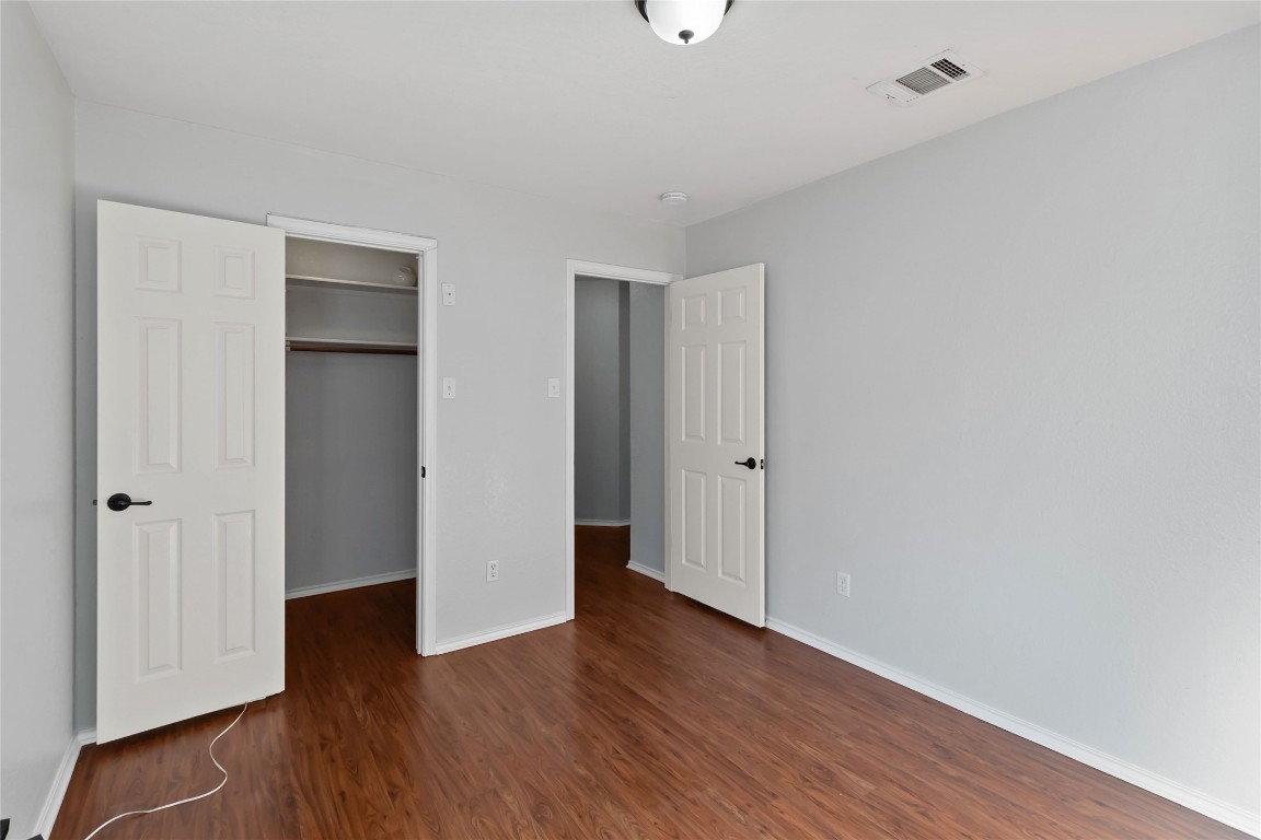1320 Lochaline Loop Pflugerville, TX 78660 - Photo 27 of 35 Unfurnished bedroom with a walk in closet and dark wood-style flooring