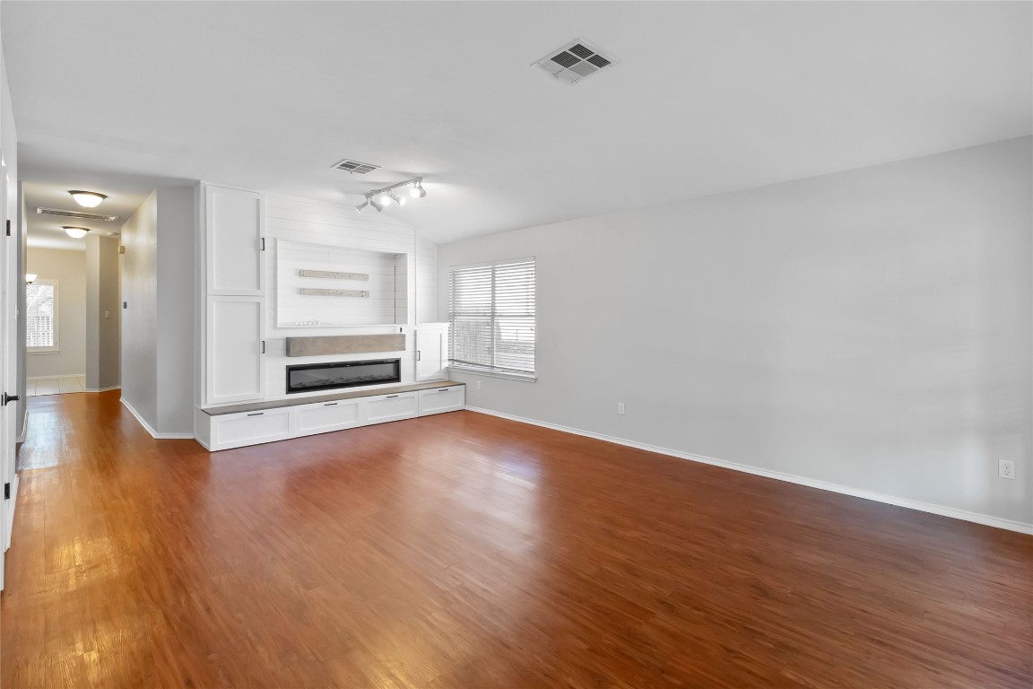1320 Lochaline Loop Pflugerville, TX 78660 - Photo 6 of 35 Unfurnished living room featuring dark wood-style flooring and lofted ceiling