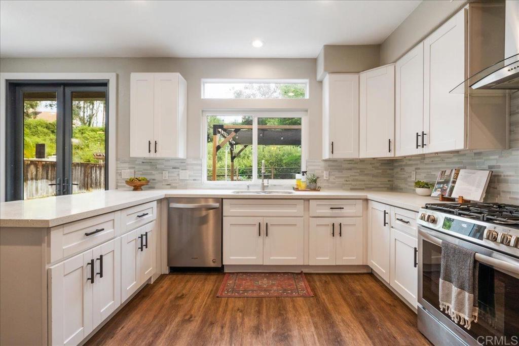 3631 Via Bernardo Oceanside, CA 92056 - Photo 9 of 38 a kitchen with a white cabinets a sink dishwasher and a stove with wooden floor